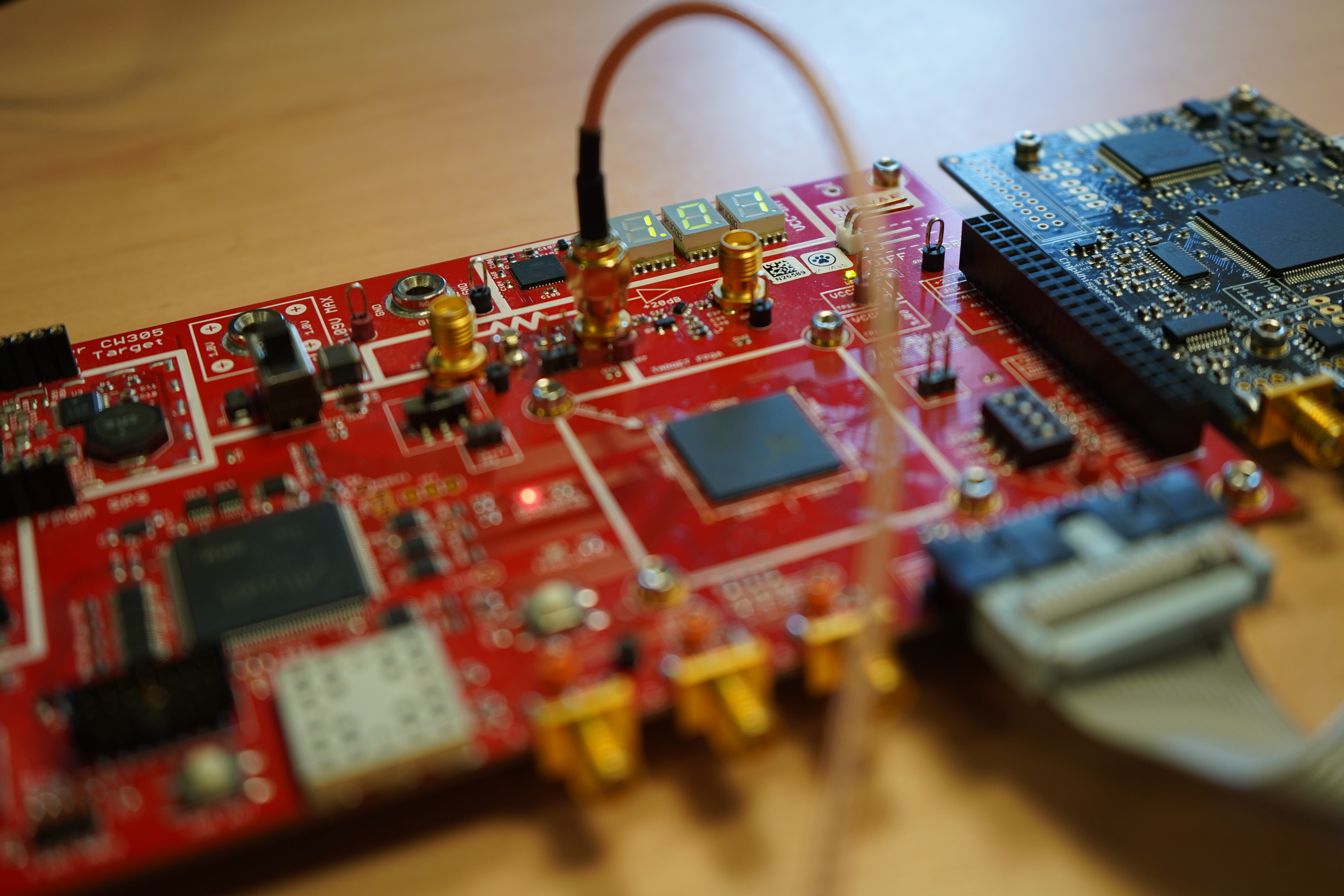 Red CW305 FPGA target board with coaxial connections and an attached evaluation board
